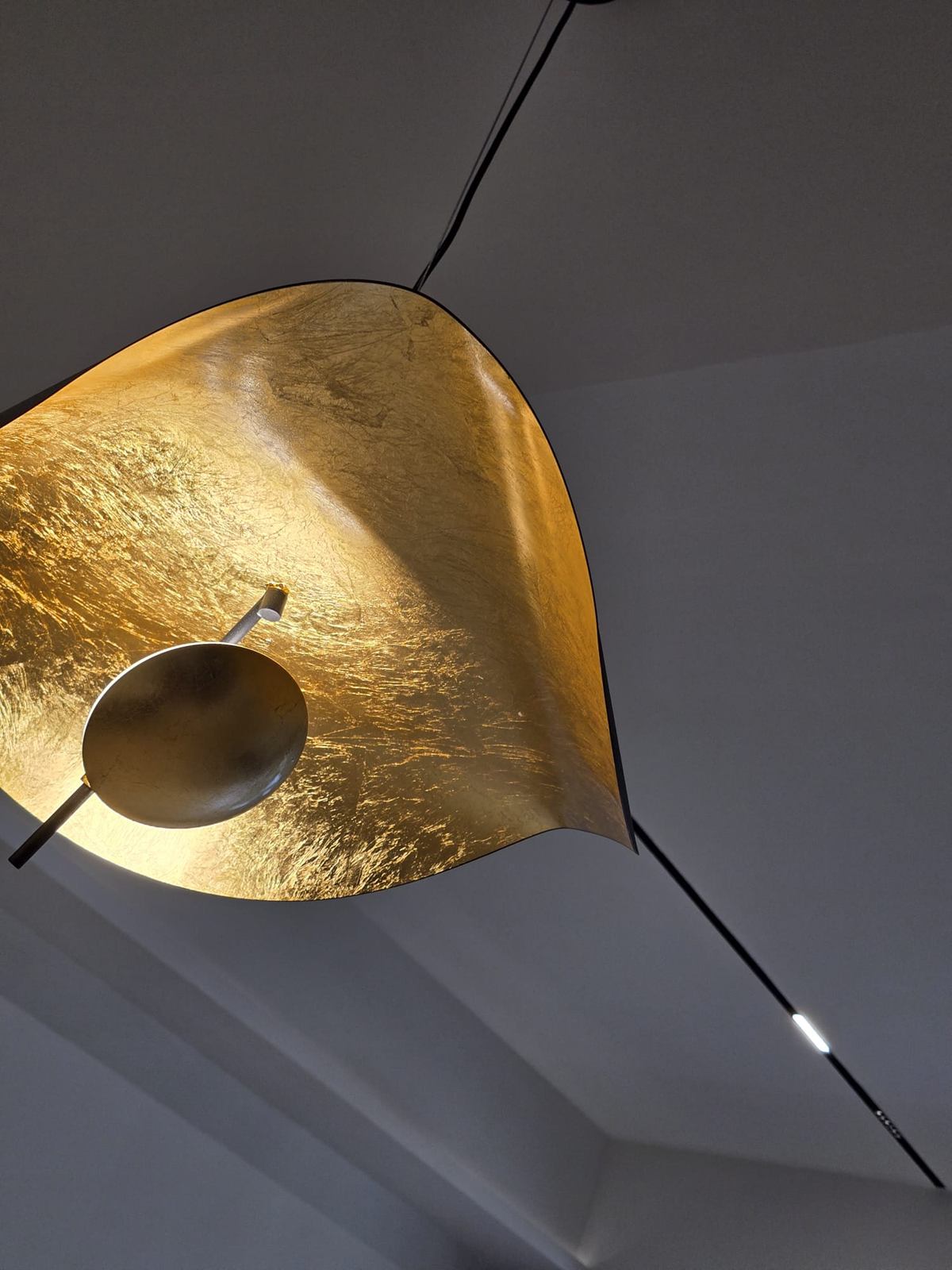 Underside of a folded gold-leaf pendant light against a pale ceiling.