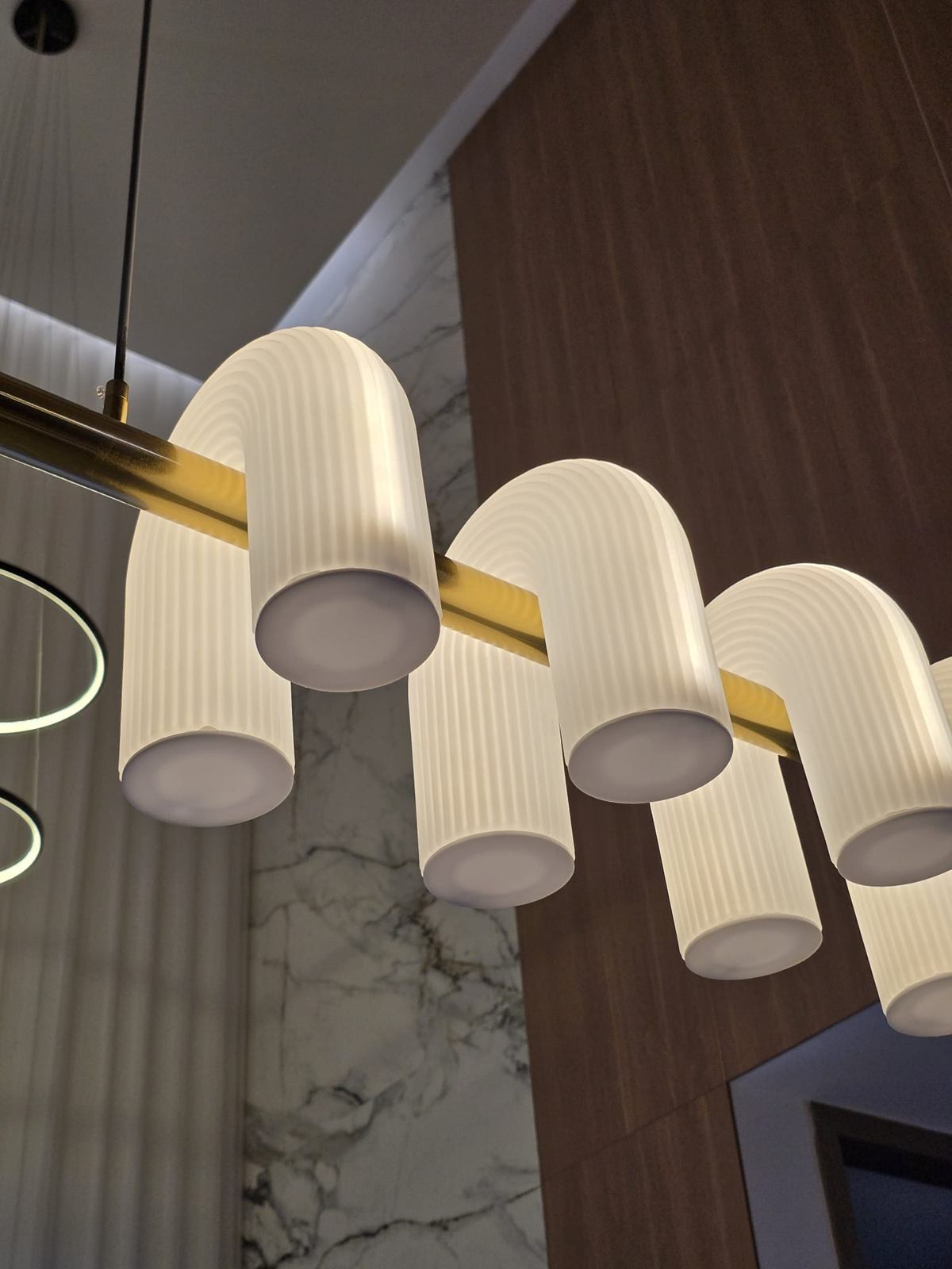 Close view of ribbed white glass shades on a brass bar.